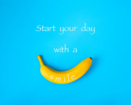 Ripe banana on blue background, text Start your day with a smile.