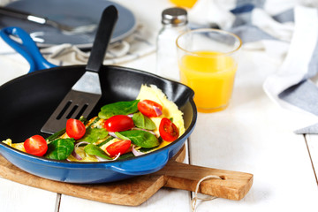Omelette with green bean, spinach and tomato in a skillet.