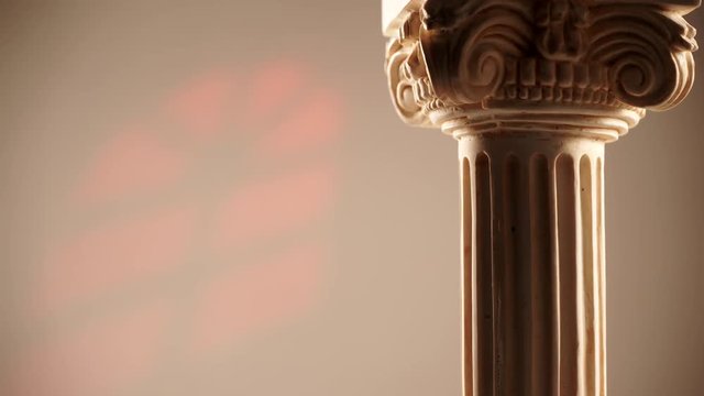 Single ancient corinthian column rotating slowly on bright wall background with window light effect