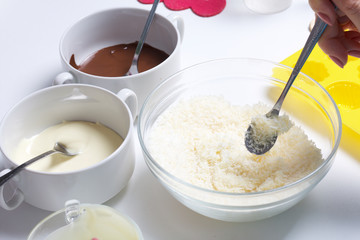 Woman adds condensed milk to coconut chips. Ingredients for dessert are on the table. Cooking sweets with coconut and condensed milk. In a glaze of white and black chocolate.