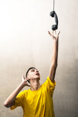 ragazzo che allunga un braccio per prendere una vecchia cornetta del telefono