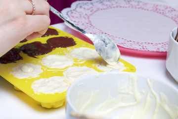 A woman smears chocolate filling coconut and condensed milk. Ingredients for dessert are on the table. Cooking sweets with coconut and condensed milk. In a glaze of white and black chocolate.