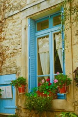 Fototapeta na wymiar Finestra con imposte azzurre e fiori, Costa Azzurra in Provenza, Francia