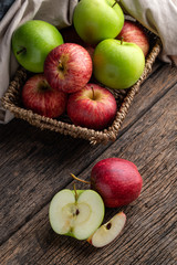 Naklejka na ściany i meble Red and green apples in basket on wooden background.