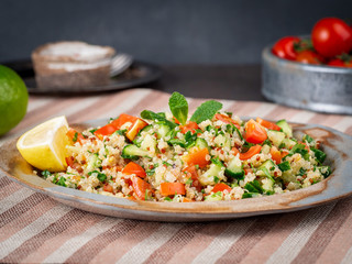 Tabbouleh salad with quinoa. Eastern food with vegetables mix, vegan diet. Side view, linen napkin, old plate