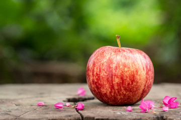 One red apple on wooden table with bokeh background.