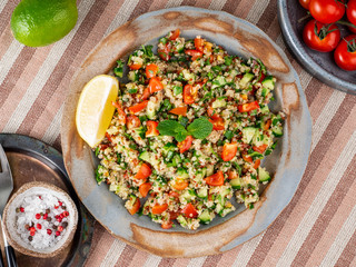 Tabbouleh salad with quinoa. Eastern food with vegetables mix, vegan diet. Top view, linen napkin, old plate