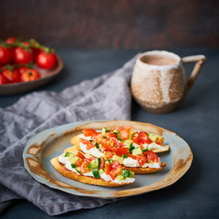 Three crostini, traditional Italian sandwich with tomatoes and cucumbers. Breakfast on plate, Cup of cocoa, dark background, side view