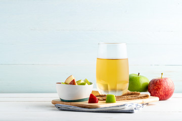 Glass of apple juice and slice green and red  apples on white wooden background.