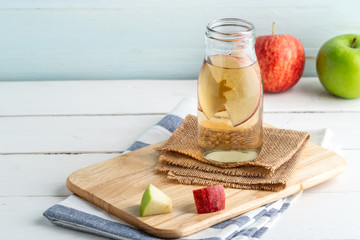 Apple juice or apple tea in a bottle on wooden background.