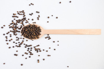 blask pepper peppercorns in wooden spoon isolated on white background. Closeup. © eyecon