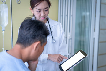 Woman doctors are explaining something from a tablet to a sick male patient.