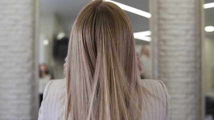 Attractive blonde woman tossing her long, wavy hair indoors in slow motion. - Powered by Adobe