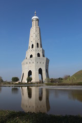 A tower alongside a small lake clicked at day time.