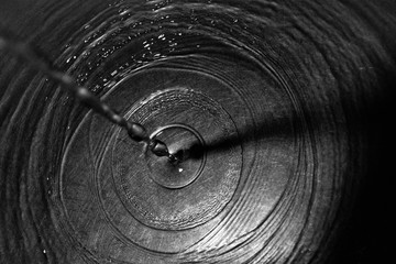 Drops of water drip out of the tap and sink and create waves