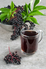 Glass with elderberry drink and clusters of berries