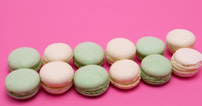 A row of colored macaroons dessert on pink background