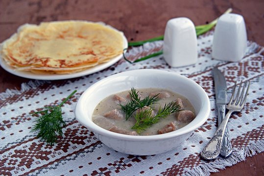 Machanka, thick sauce on meat broth with homemade pork sausages in a white bowl. Served with thin wheat pancakes. Belarusian cuisine