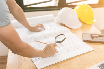 architect or civil engineer checking or inspected builing plan with magnifier in office.