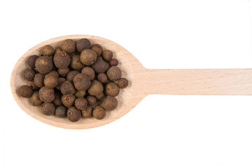 allspice on wooden spoon isolated on white background