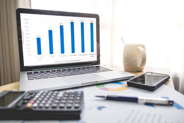 Business financial concept , Laptop ,pen, coffee,smartphone, graph for finance and business on the table