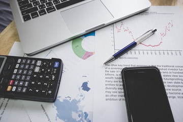 Business financial concept , Laptop ,pen, coffee,smartphone, graph for finance and business on the table