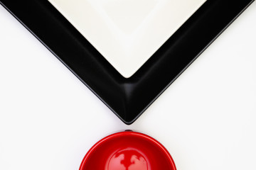 Different black and white plates and red cup on the white wooden table.Top view. Flat Lay Image.