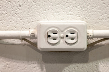Old rustic North American electrical outlet on a white brick wall