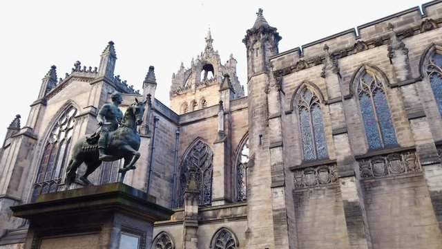Pan down from Charles II (Equestrian Statue) in Parliament Square to the back of St Giles' Cathedral on a cloudy day, Edinburgh, Lothian, UK