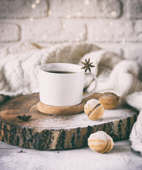 Cup of tea, cookies are on the stump. Near a white sweater and a garland. Good mood. Toned photo