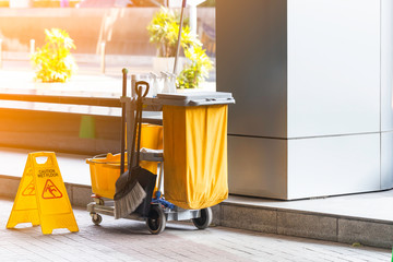 Janitorial and mop bucket on cleaning with caution wet floor.
