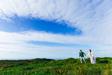 Obraz premium The guy holds the girl by the hand and they walking on green gra