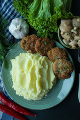 Pork cutlets with mashed potatoes, greens and fresh vegetables on a black background. View from above.