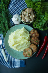 Pork cutlets with mashed potatoes, greens and fresh vegetables on a black background. View from above.