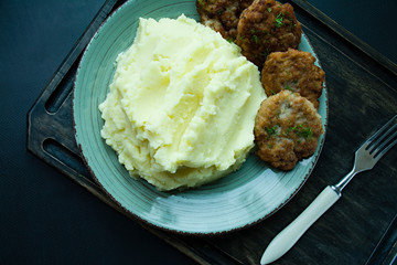 Pork cutlets with mashed potatoes, greens on a black background. View from above.