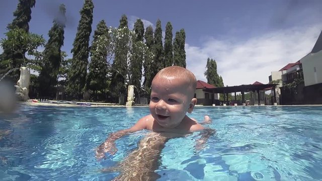 Happy smiling toddler is diving under water with father