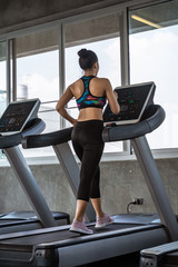Fototapeta premium beautiful asian girl is walking on a treadmill in the gym.She Send your eyes with pleasure in exercise because it makes her shapely, the concept of exercise, lose weight, strengthen muscles.