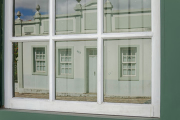 Detalhe de janela colonial com reflexo de casa colonial de Santa Luzia, estado de Minas Gerais., Brasil.