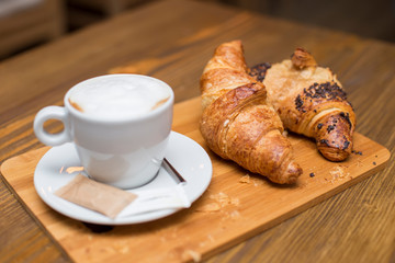 Traditional french breakfast with cups of hot coffee and fresh tasty croissants placed on vintage table