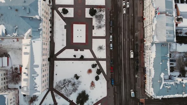 Aerial flight of drone along city road with cars and buildings top down view