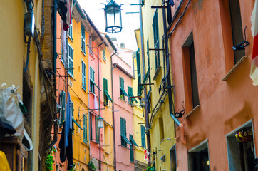 Narrow street with colorful multicolored buildings houses of Portovenere town village with street lamps, shutters on windows, National park Cinque Terre, La Spezia, Liguria, Italy