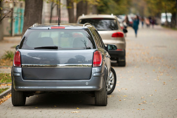 Gray shiny car parked in quiet area on asphalt road on blurred bokeh background on bright sunny...