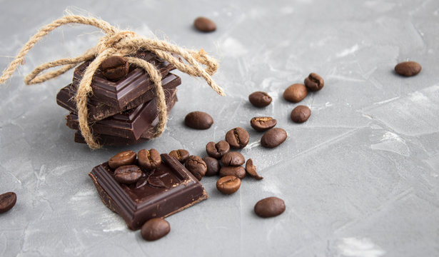 three thick pieces of chocolate tied by a linen rope and coffee beans, soft focus, on a gray background