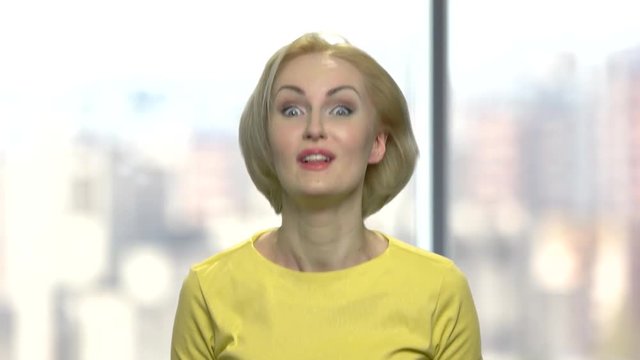 Beautiful blonde woman making silly expression. Middle-aged playful woman making funny face standing on blurred background.