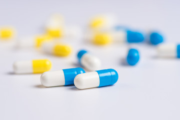Yellow and blue pills or capsules on a white background