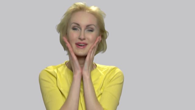 Beautiful excited woman fooling around. Slow motion funny middle-aged woman having fun on gray background. Human facial expressions.