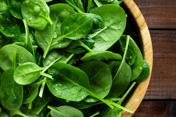 Fresh spinach leaves on wooden background. Healthy vegan food. Top view.