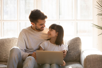 Happy dad and daughter having fun using laptop at home