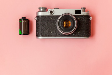 Technology development hipster photographer hobby classic memory trip concept. Vintage film photo camera lens and film roll on pink pastel trendy modern fashion pin-up background