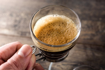 Man holding coffee glass and coffee grain on wooden table. 